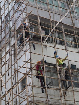 Workers on bamboo scaffolding in Hong Kong building construction, showcasing traditional techniques.